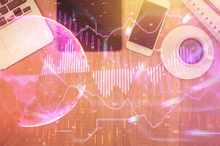 Double exposure of financial chart hologram over desktop with phone. Top view. Mobile trade platform concept.の写真素材