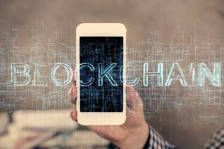 Double exposure of mans hands holding and using a phone and crypto currency blockchain theme...