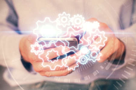 Double exposure of mans hands holding and using a phone and international business theme drawing.