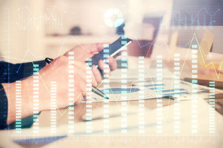 Double exposure of mans hands holding and using a phone and financial graph drawing. Analysis...