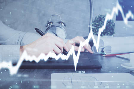 Double exposure of mans hands holding and using a phone and financial graph drawing. Analysis...