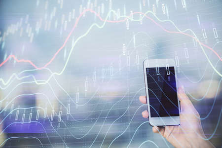 Double exposure of forex chart sketch hologram and woman holding and using a mobile device. Stock...