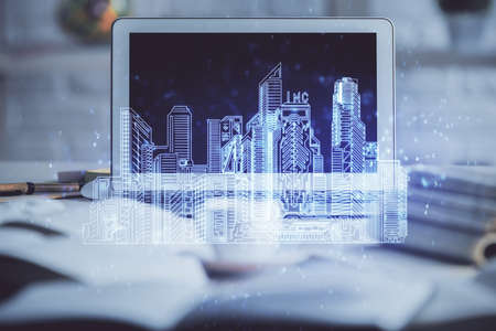 Desktop computer background in office and big town buildings hologram drawing. Double exposure....