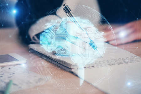 Double exposure of womans writing hand on background with brain hud. Concept of learning.