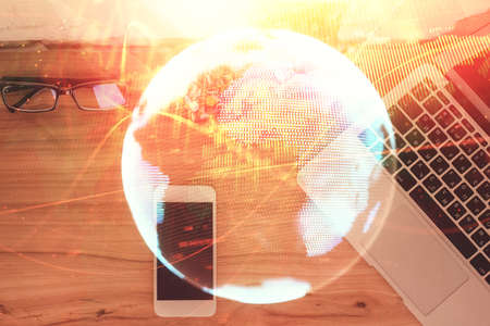 Double exposure of business theme hologram over desktop with phone. Top view. Mobile international trade connection concept.の写真素材