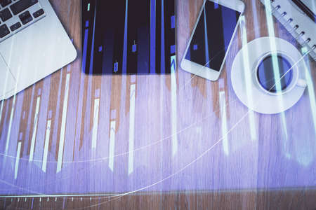 Double exposure of financial graph hologram over desktop with phone. Top view. Mobile trade platform concept.の写真素材