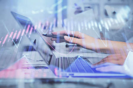Multi exposure of woman hands typing on computer and financial graph hologram drawing. Stock market...