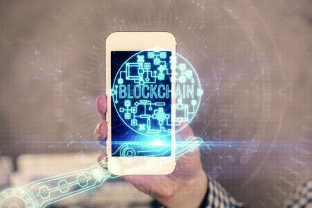 Double exposure of mans hands holding and using a phone and crypto currency blockchain theme...