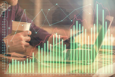 Double exposure of mans hands holding and using a phone and financial graph drawing. Analysis...