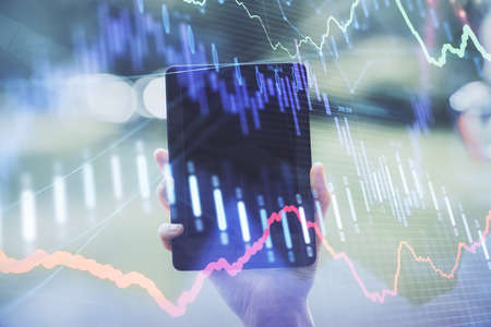 Double exposure of forex chart sketch hologram and woman holding and using a mobile device....
