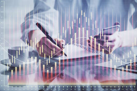 Double exposure of financial graph sketch hologram and woman holding and using a mobile device....