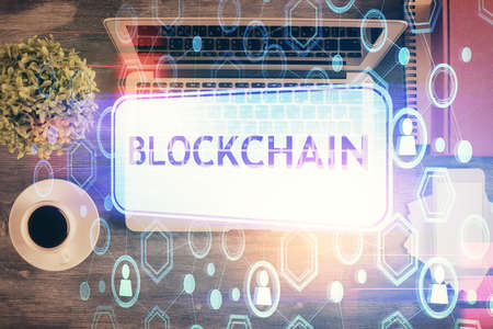 Blockchain theme hologram drawings over computer on the desktop background. Top view. Double...