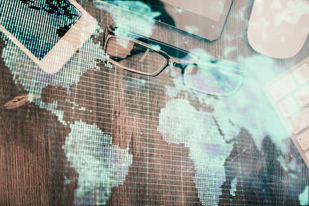 Double exposure of business theme hologram over desktop with phone. Top view. Mobile international...