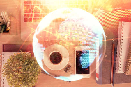 Double exposure of business theme hologram over desktop with phone. Top view. Mobile international...