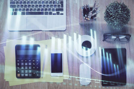 Double exposure of forex chart hologram over desktop with phone. Top view. Mobile trade platform...