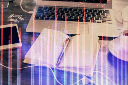 Multi exposure of financial graph drawings and desk with open notebook background. Concept of forex