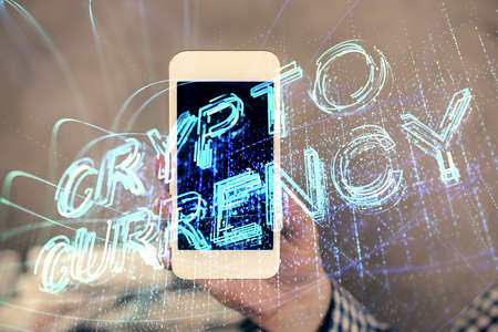 Double exposure of mans hands holding and using a phone and crypto currency blockchain theme...