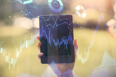 Double exposure of forex chart sketch hologram and woman holding and using a mobile device....