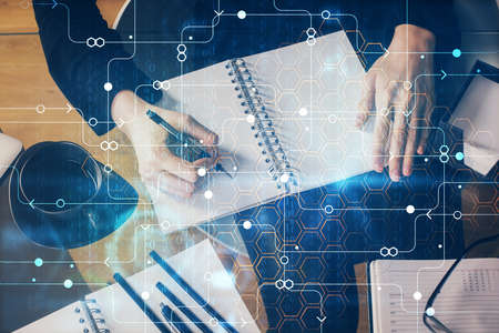Double exposure of writing hands on background with data solution hologram on front. Technology...