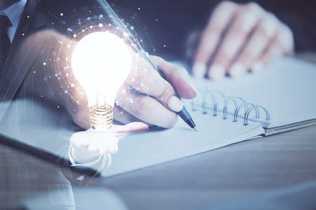 Drawing bulb over womans hands taking notes background. Concept of idea. Double exposure