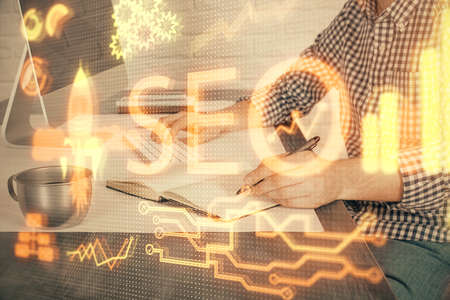 Double exposure of seo icon with man working on computer on background. Concept of search engine optimization.の写真素材