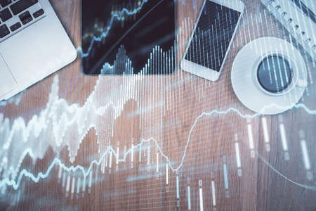 Double exposure of financial graph hologram over desktop with phone. Top view. Mobile trade platform concept.の写真素材