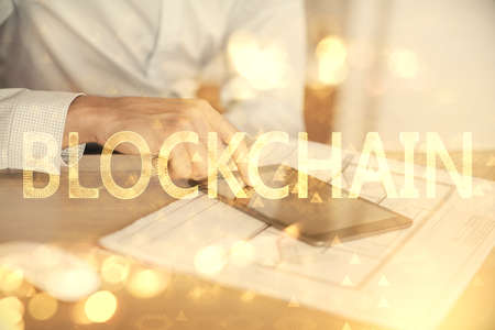 Double exposure of mans hands holding and using a phone and crypto currency blockchain theme...