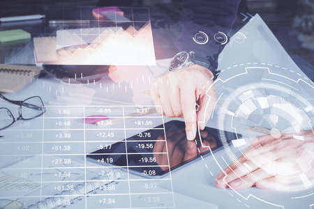 Double exposure of mans hands holding and using a digital device and forex graph drawing. Financial...