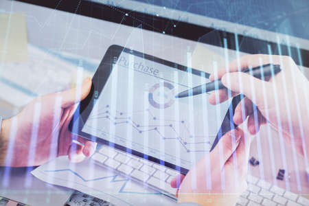 Double exposure of mans hands holding and using a phone and financial chart drawing. Market analysis...
