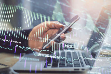 Double exposure of mans hands holding and using a phone and financial graph drawing. Analysis...