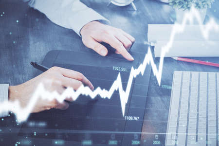 Double exposure of mans hands holding and using a phone and financial graph drawing. Analysis...