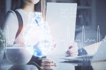 Heart hologram over womans hands writing background. Concept of Medical education study. Double...
