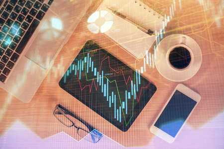 Double exposure of financial graph hologram over desktop with phone. Top view. Mobile trade platform concept.の写真素材