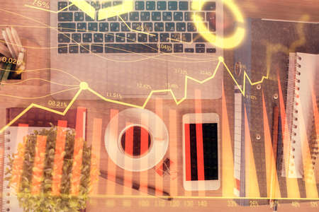 Double exposure of financial graph hologram over desktop with phone. Top view. Mobile trade platform...