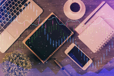 Double exposure of forex chart hologram over desktop with phone. Top view. Mobile trade platform...