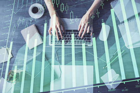 Multi exposure of woman hands working on computer and forex chart hologram drawing. Top View....