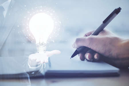 Drawing bulb over womans hands taking notes background. Concept of idea. Double exposureの写真素材