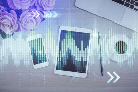 Double exposure of forex graph hologram over desktop with phone. Top view. Mobile trade platform...