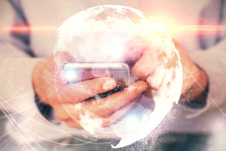 Double exposure of mans hands holding and using a phone and international business theme drawing.