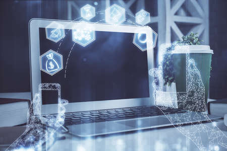 Computer on desktop in office with technology theme hologram. Double exposure. Tech concept.