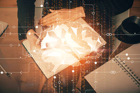 Double exposure of writing hand on background with brain hologram. Concept of learning.