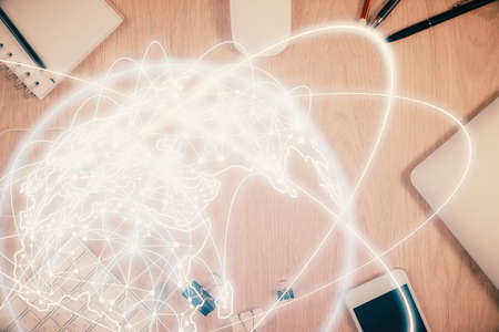 Double exposure of business theme hologram over desktop with phone. Top view. Mobile international...