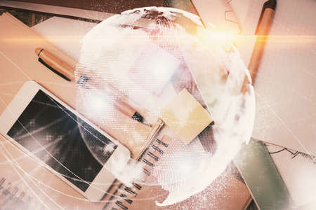 Double exposure of business theme hologram over desktop with phone. Top view. Mobile international trade connection concept.の写真素材