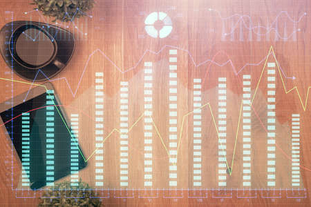 Multi exposure of financial chart hologram over desktop with phone. Top view. Mobile trade platform...