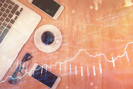 Double exposure of financial graph hologram over desktop with phone. Top view. Mobile trade platform concept.の写真素材