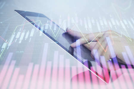 Multi exposure of mans hands holding and using a digital phone and forex graph drawing. Financial...