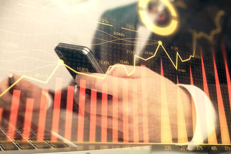 Multi exposure of mans hands holding and using a digital phone and forex graph drawing. Financial...