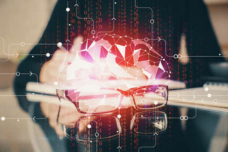 Double exposure of writing hand on background with brain hologram. Concept of learning.
