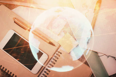 Double exposure of business theme hologram over desktop with phone. Top view. Mobile international...