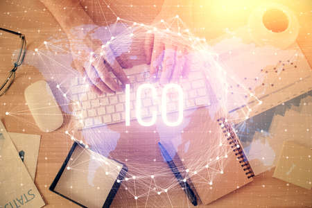 Double exposure of mans hands typing over computer keyboard and crypto currency theme hologram...